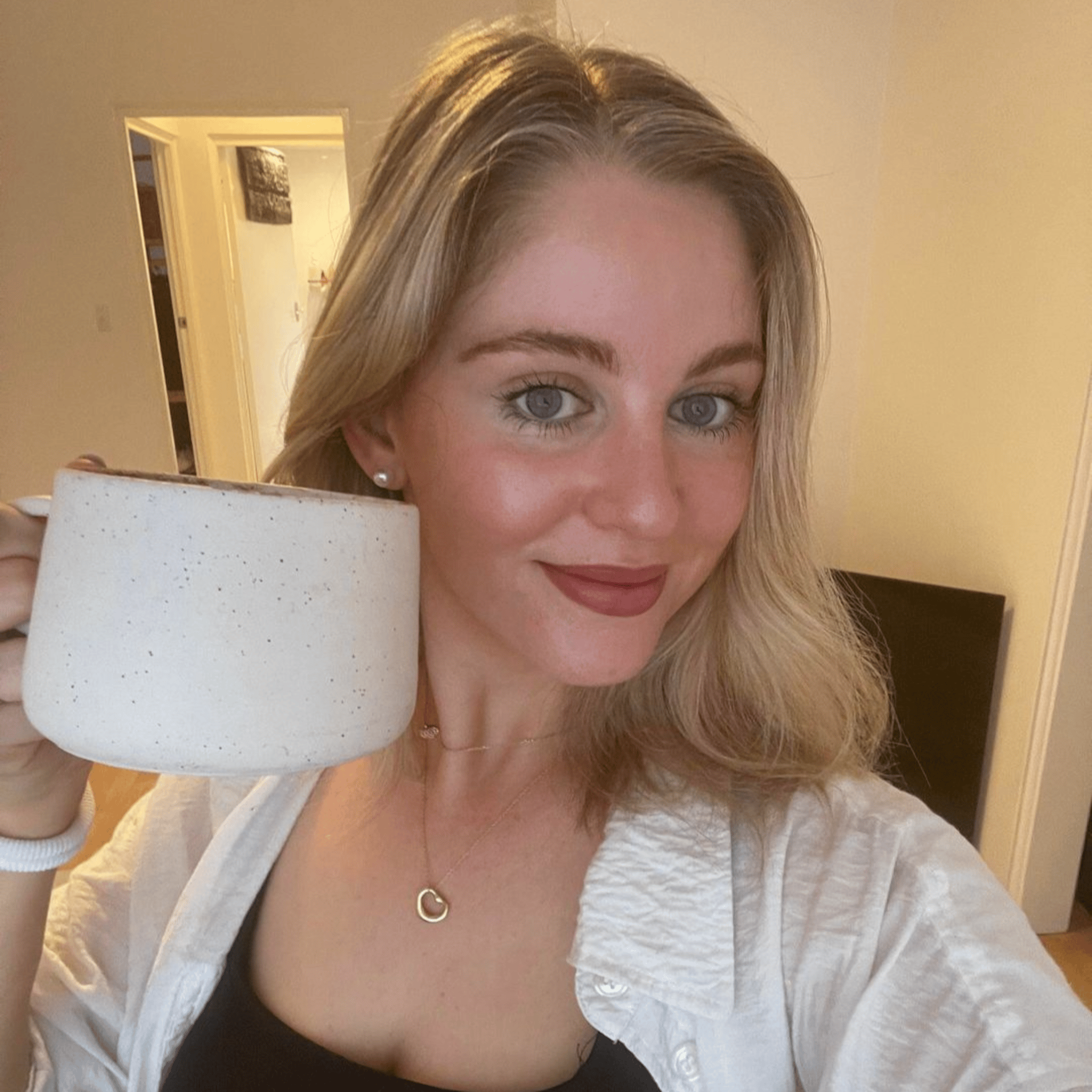 Person holding a large white mug, smiling indoors.