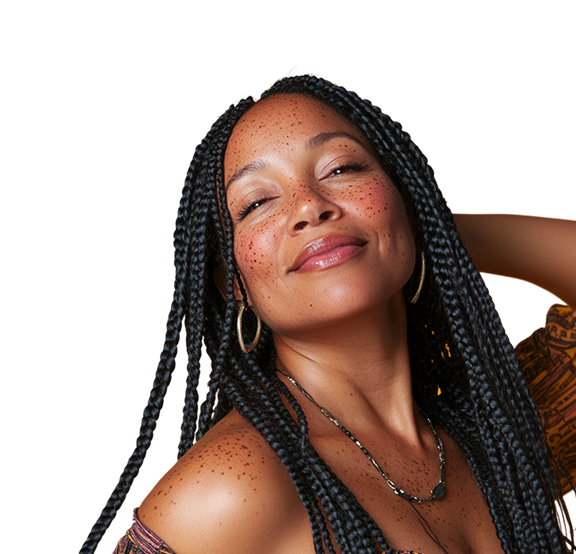 Smiling person with long braided hair and freckles, wearing hoop earrings.