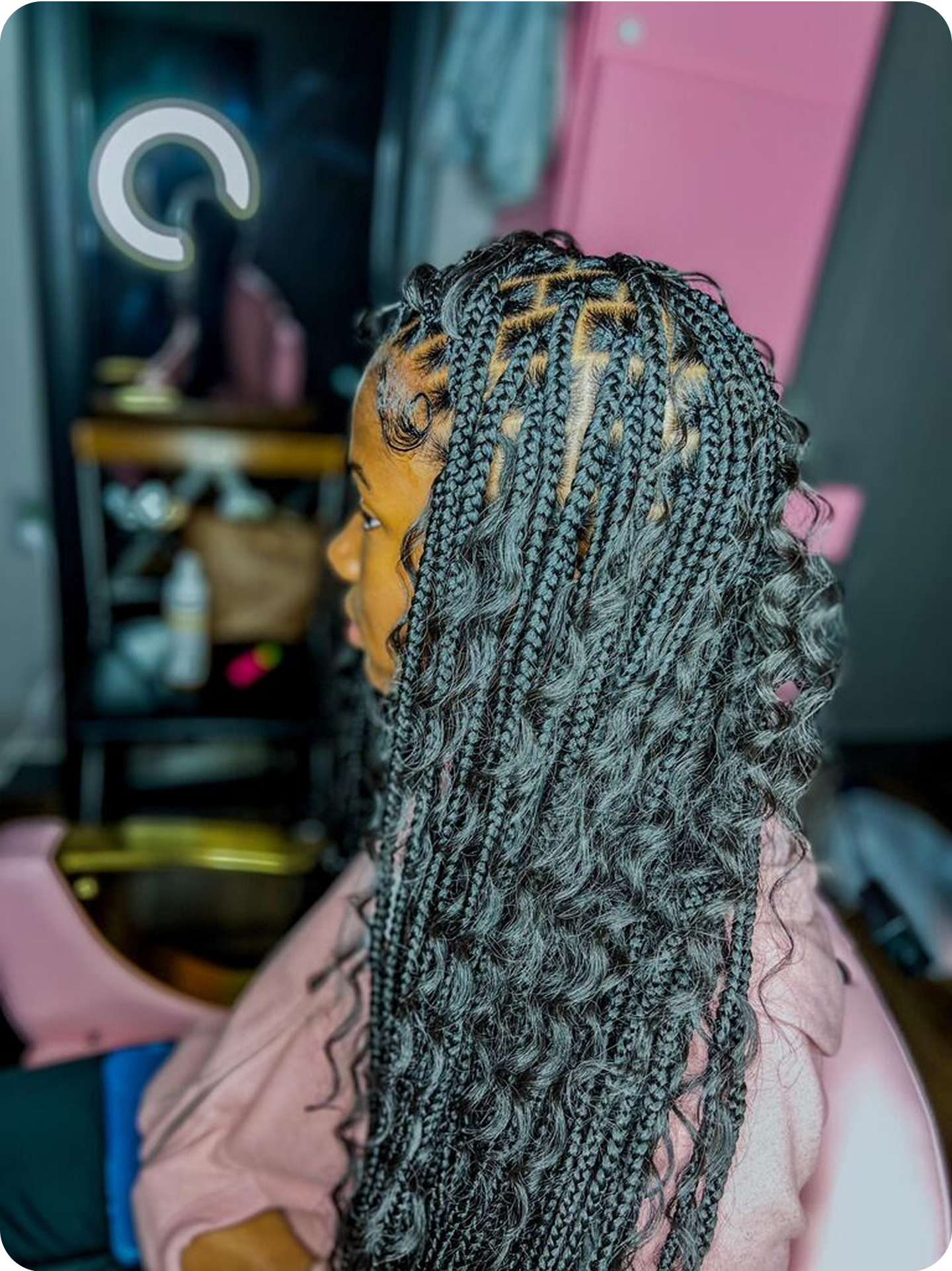 Person with long braided hair sitting in a salon chair.