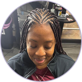 Person with braided hair sitting in a salon chair.
