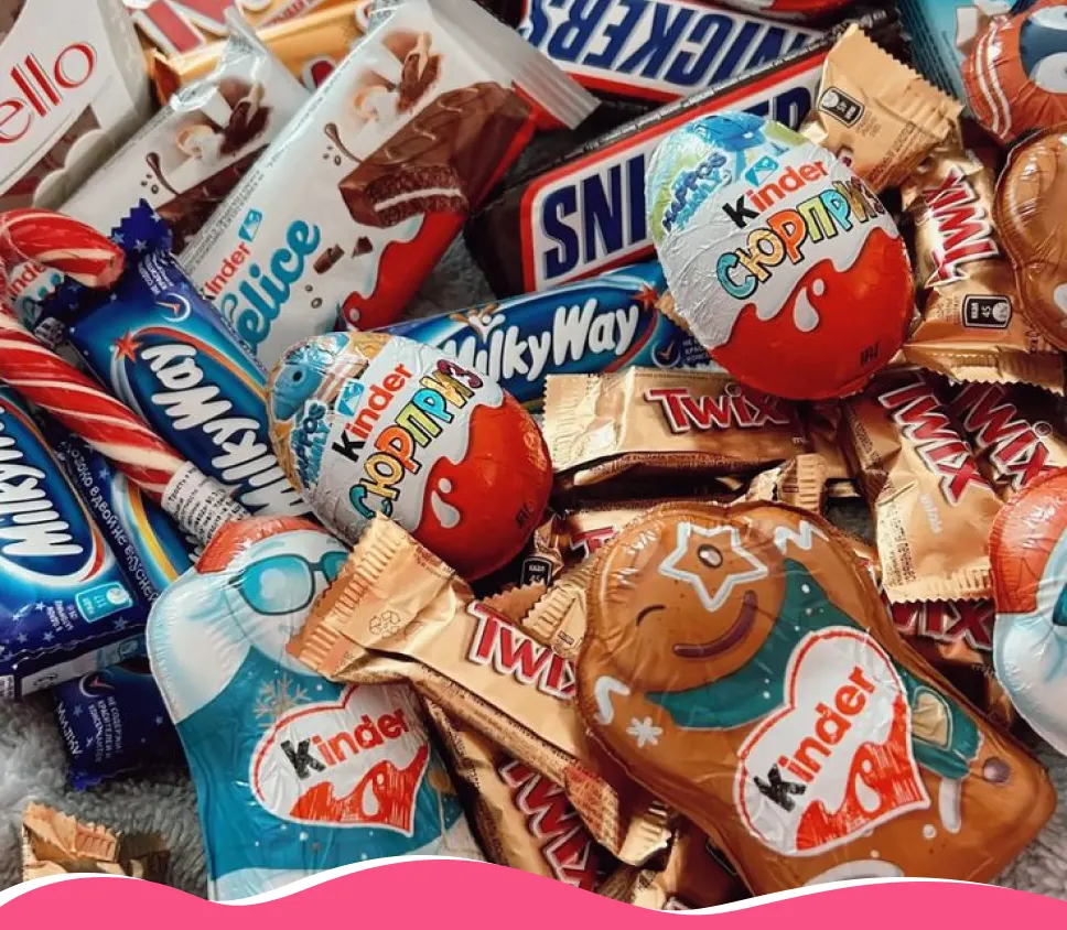 A large pile of assorted chocolate bars and candies including Kinder, Twix, Milky Way, and Snickers.