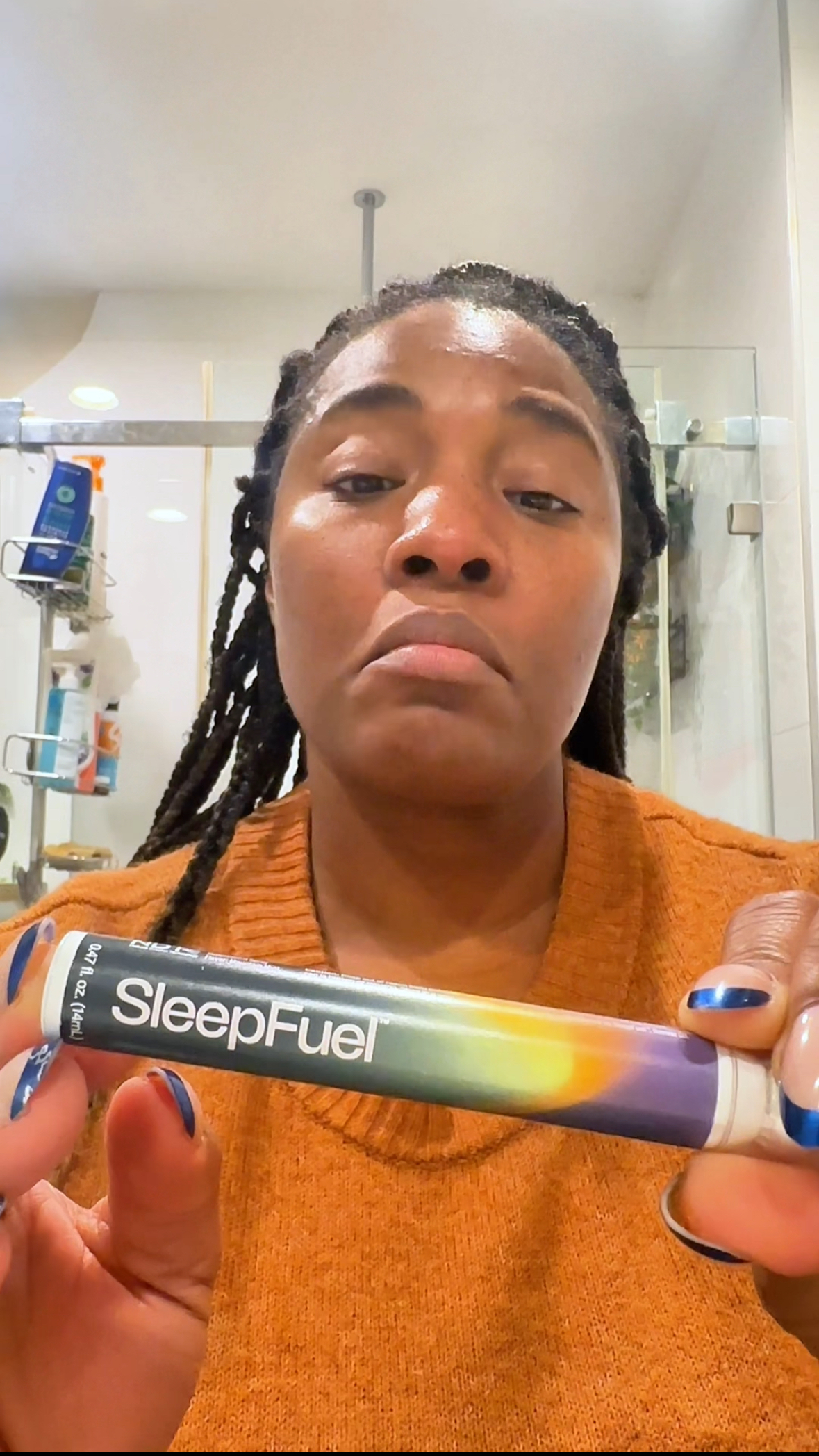 Person holding a tube labeled 'SleepFuel' in a bathroom.