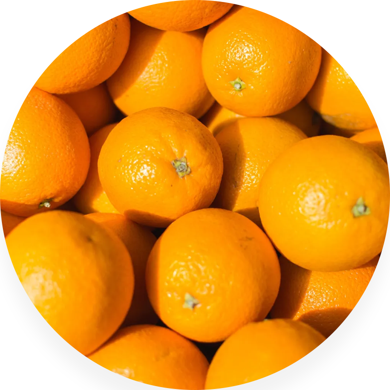 A circular image of fresh, ripe oranges piled together.