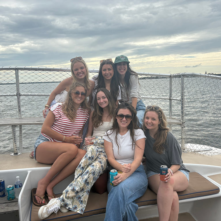 A group of people sitting on a boat holding drinks.