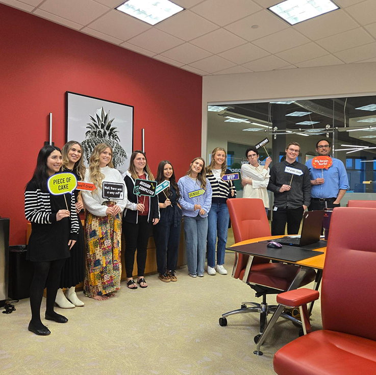People standing along a red wall holding various signs.