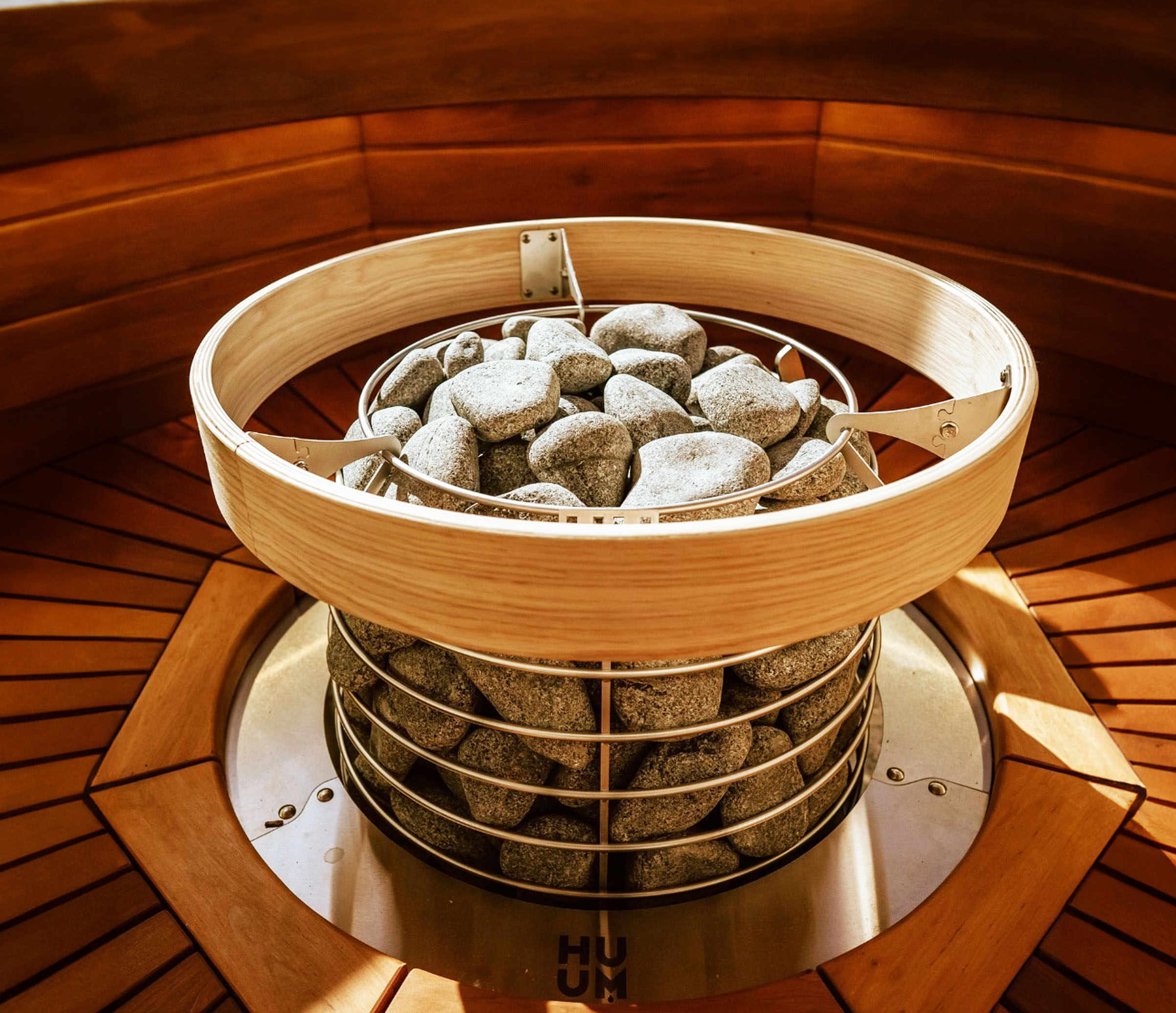 Sauna heater with stones inside a wooden enclosure.