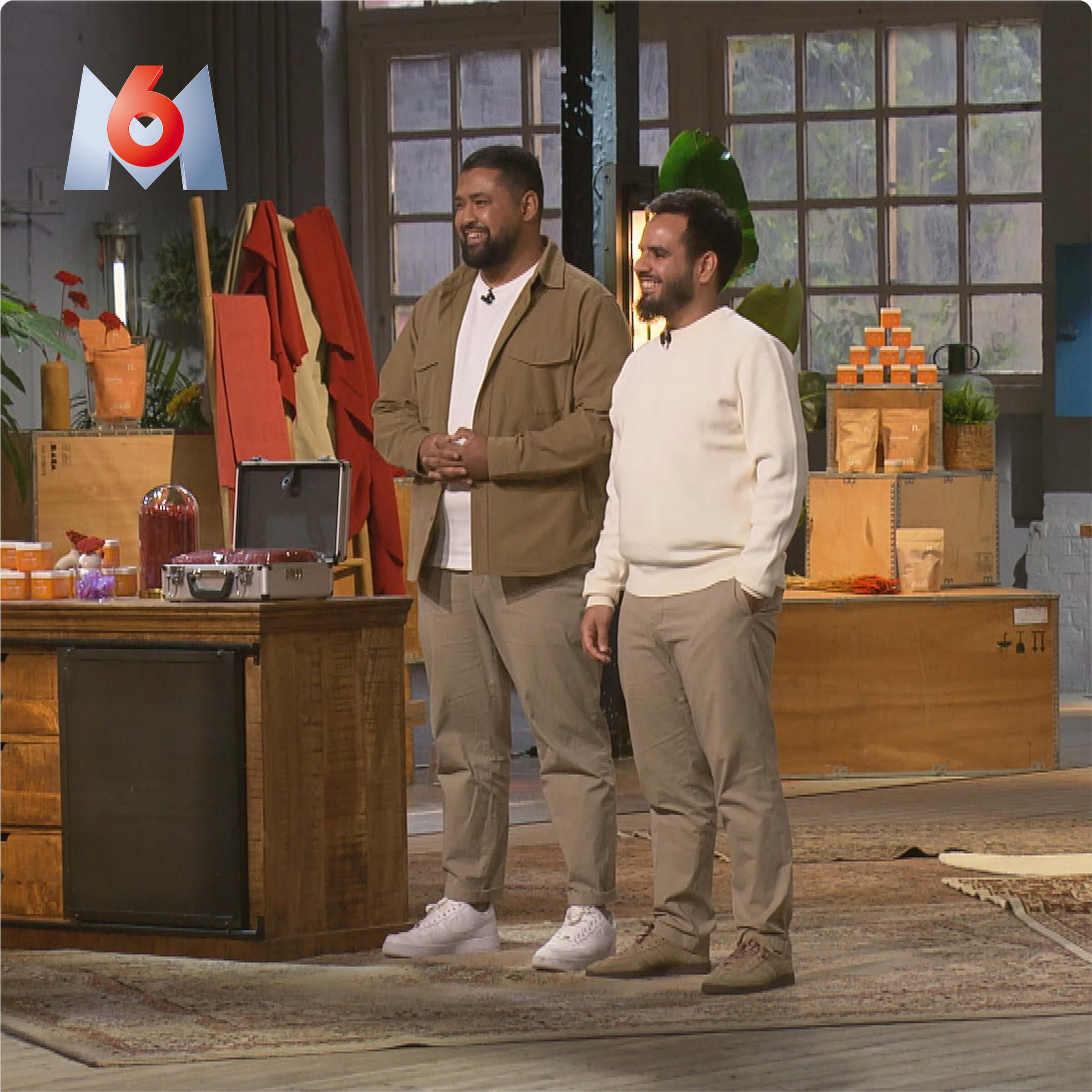 Two people presenting products in a studio setting with packaging boxes.