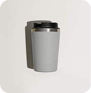 A gray travel mug with a black lid, casting a shadow on a light surface.