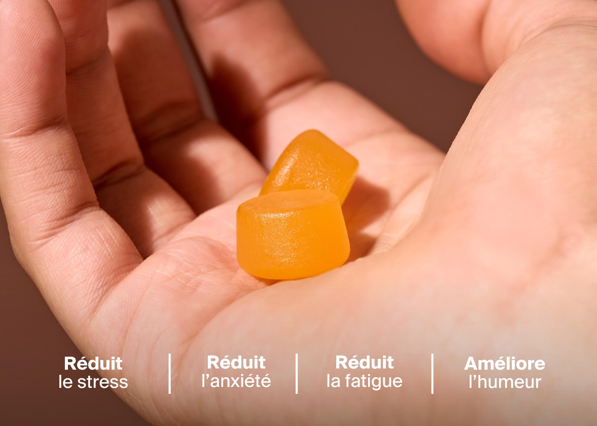Two orange gummies in a person's hand.