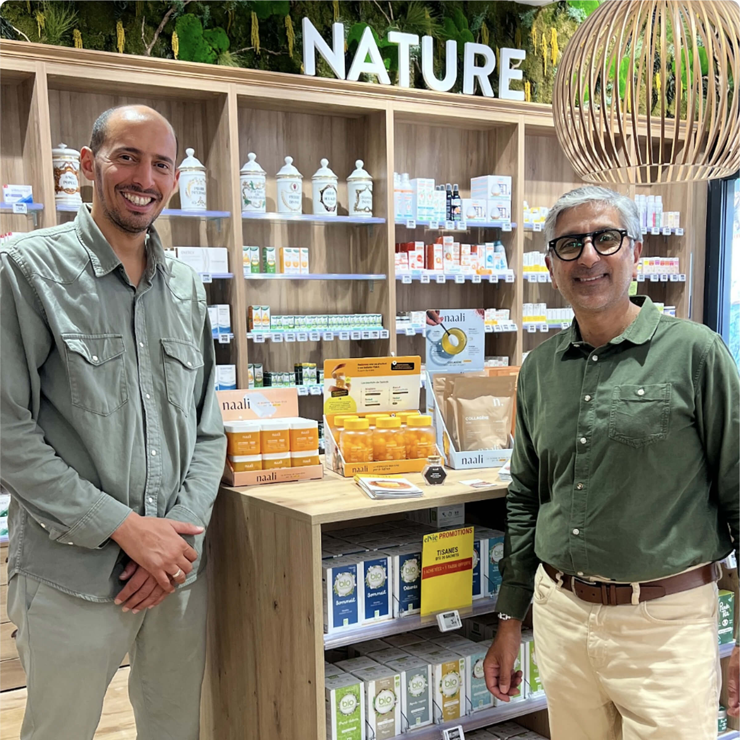 Two people stand smiling in a health store with natural products.