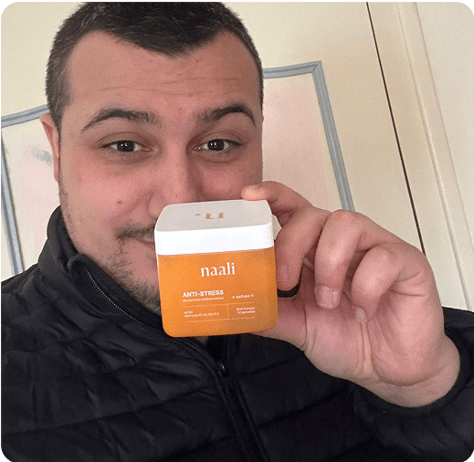 Person holding an orange container labeled 'naali' with a white cap.