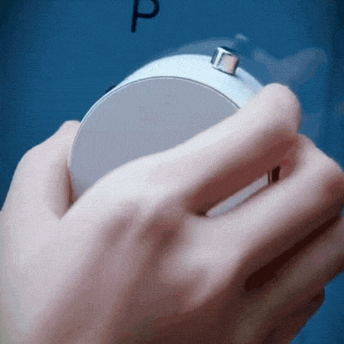 Hand adjusting a round, white thermostat on a blue wall.