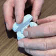 Hands opening a small white container on a wooden surface.