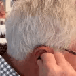 Person touching their ear with a hand, seen from the side.
