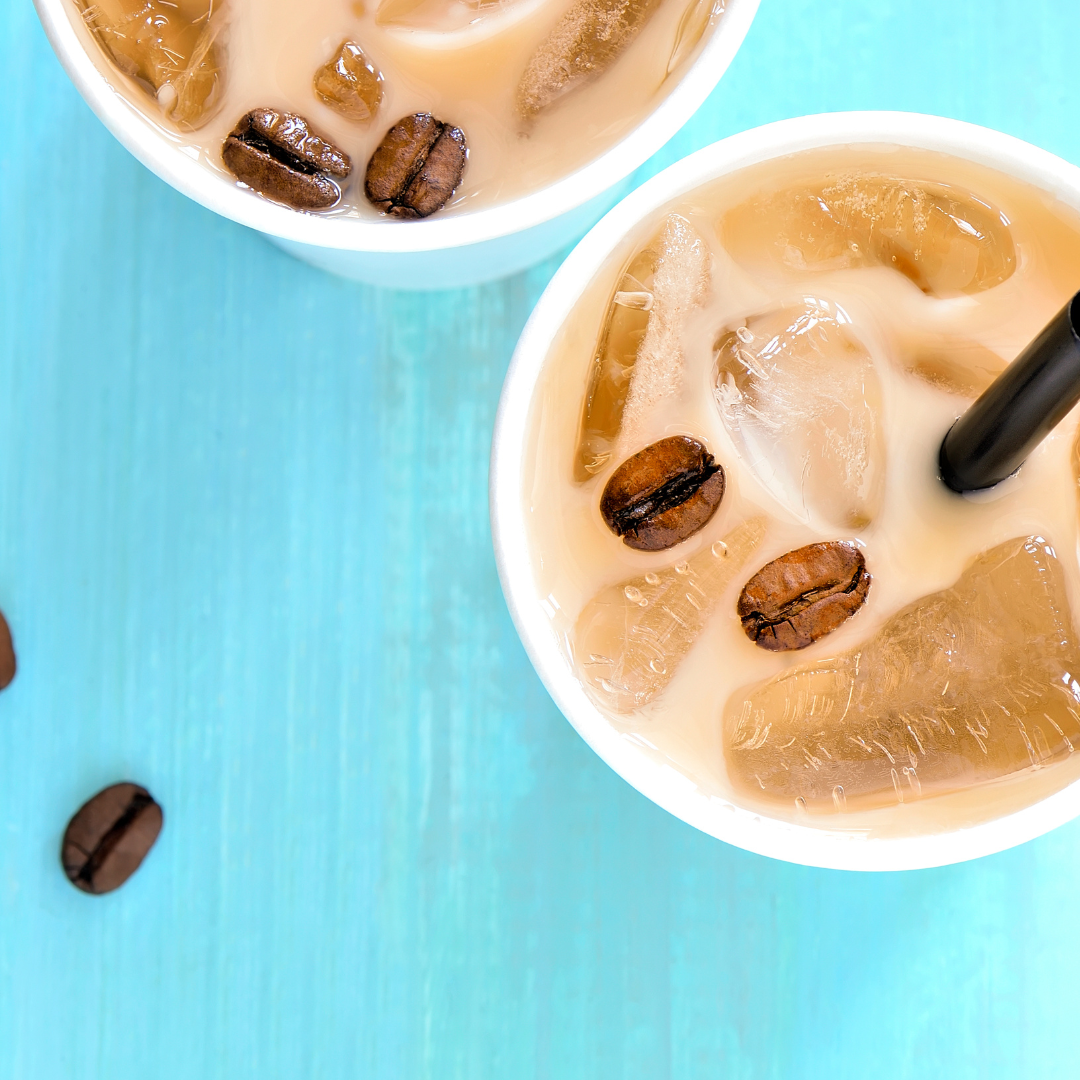 Two iced coffee drinks with coffee beans on a blue surface.