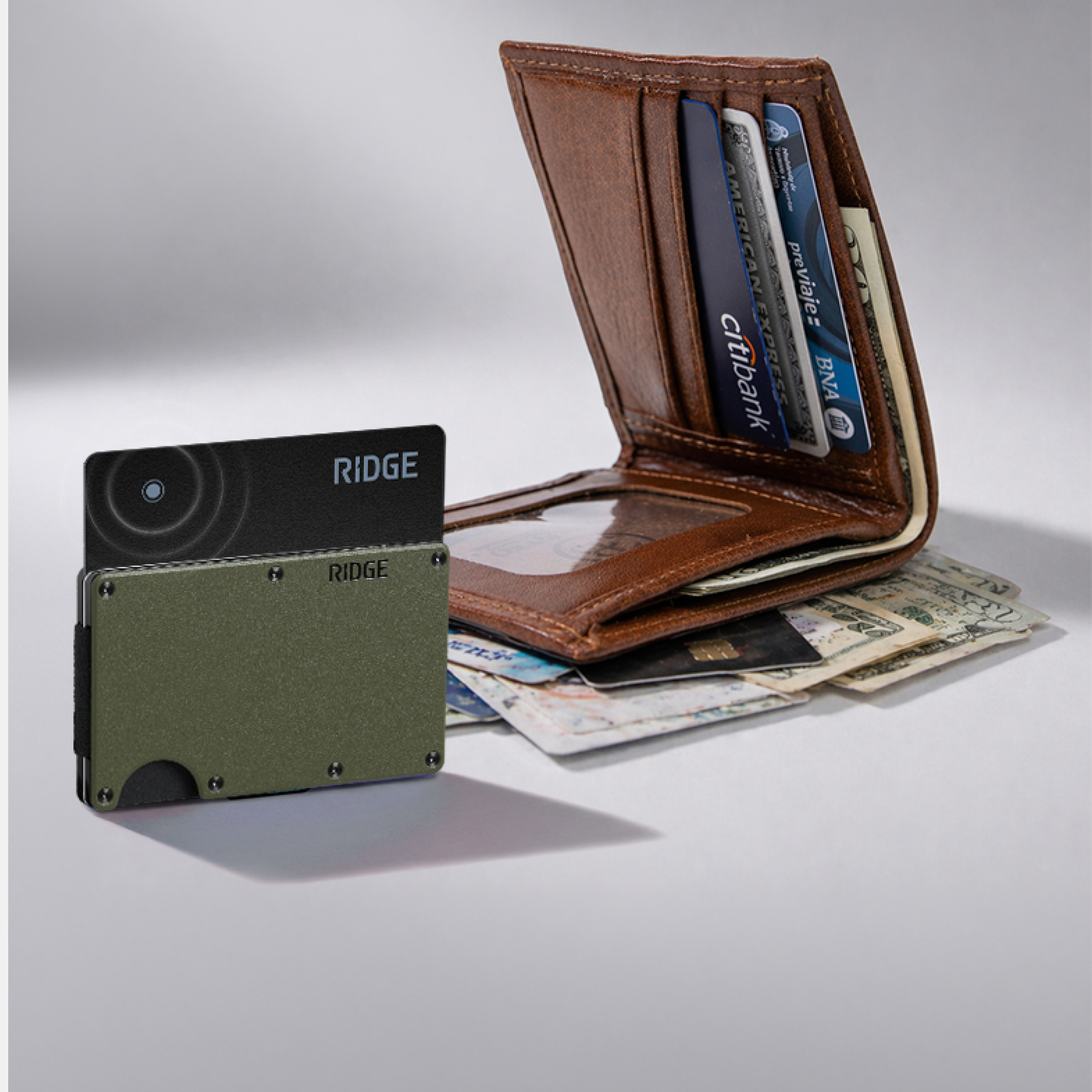 A slim, green Ridge wallet stands in front of a bulky, overstuffed brown leather bifold wallet.