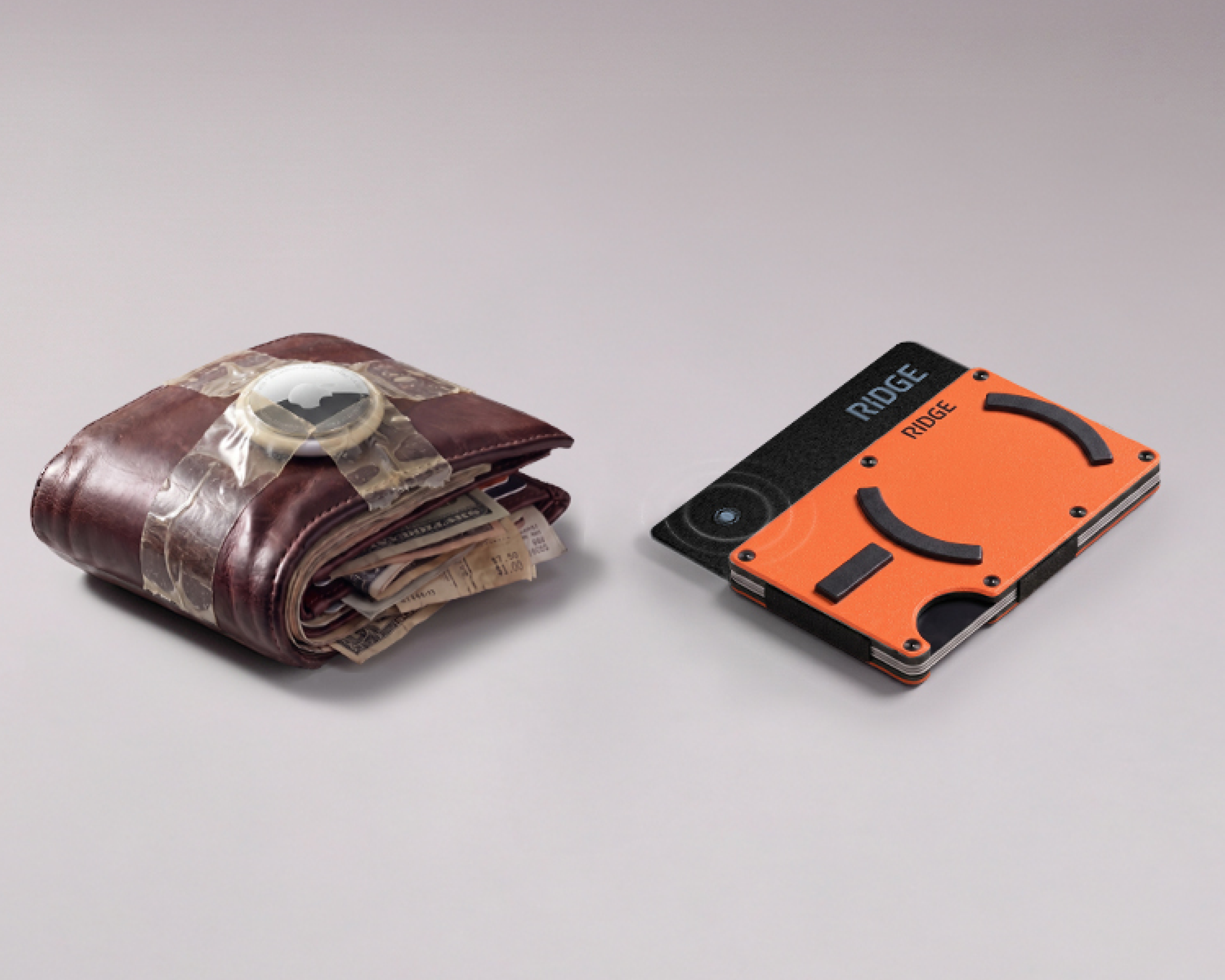 A bulky brown leather wallet with an AirTag taped on, next to a slim orange Ridge wallet.