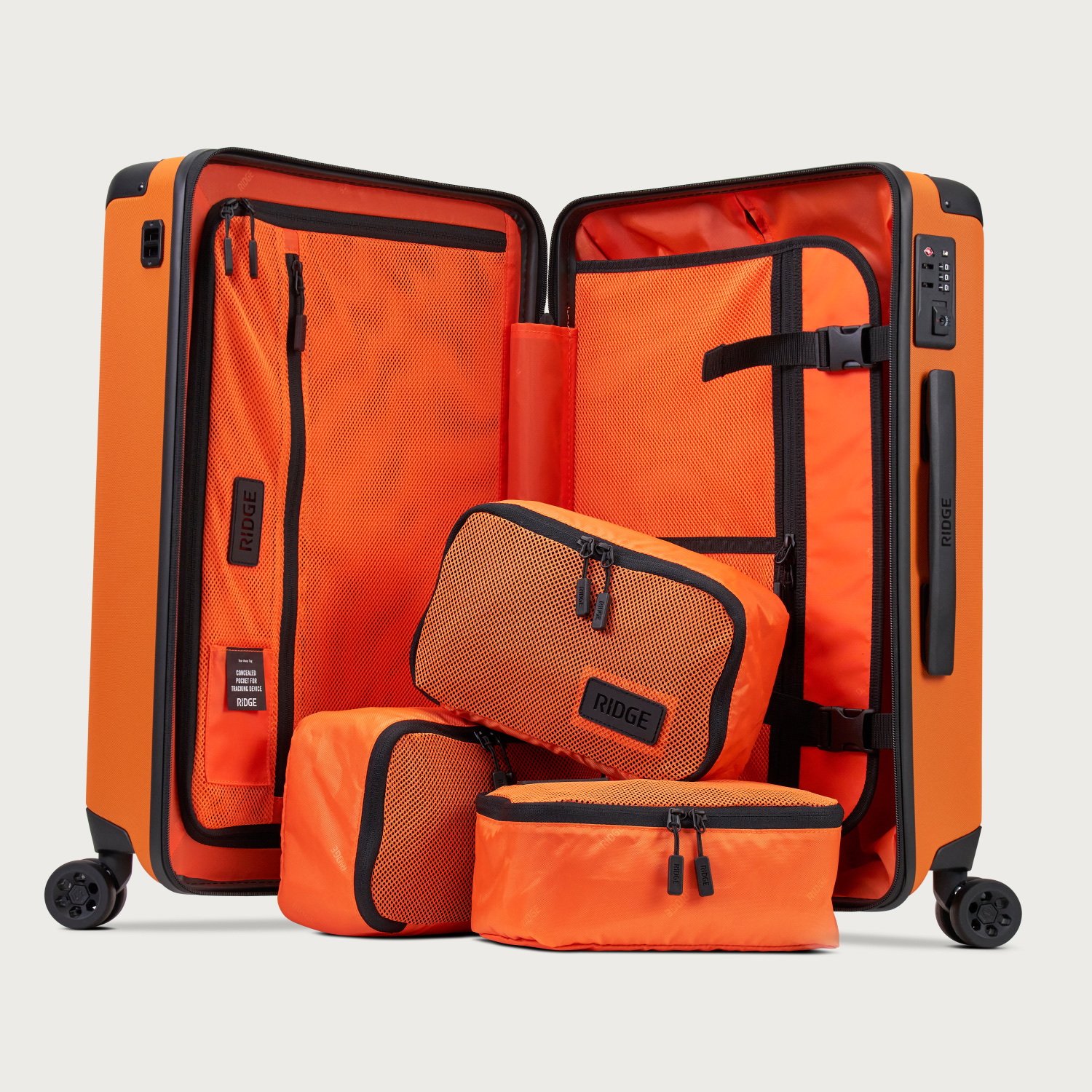 An open, bright orange rolling suitcase with three matching packing cubes against a light gray background.