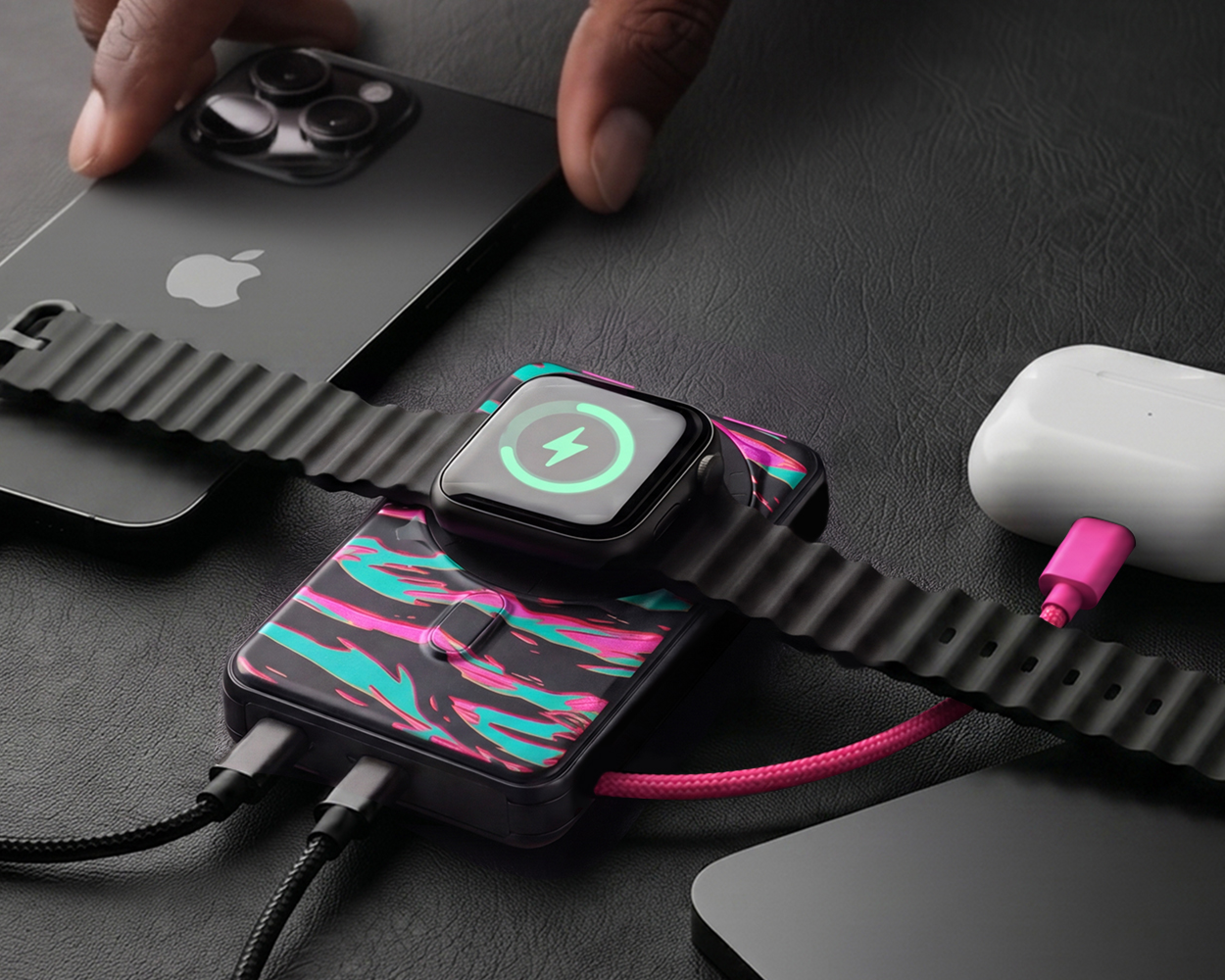 A patterned power bank charging an Apple Watch, iPhone, and AirPods on a black textured surface.