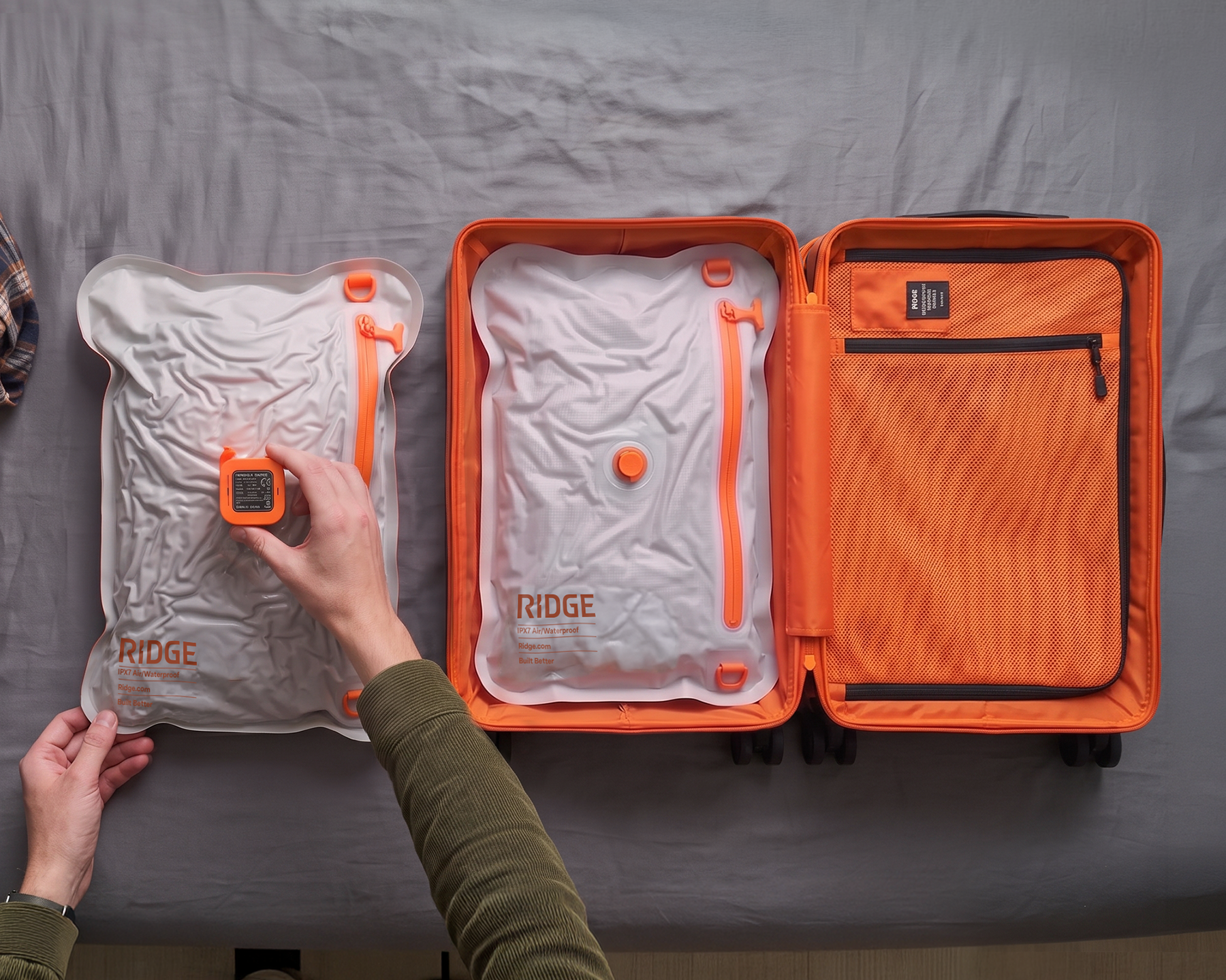 A person vacuum-sealing a white packing cube next to an open orange suitcase on a bed.