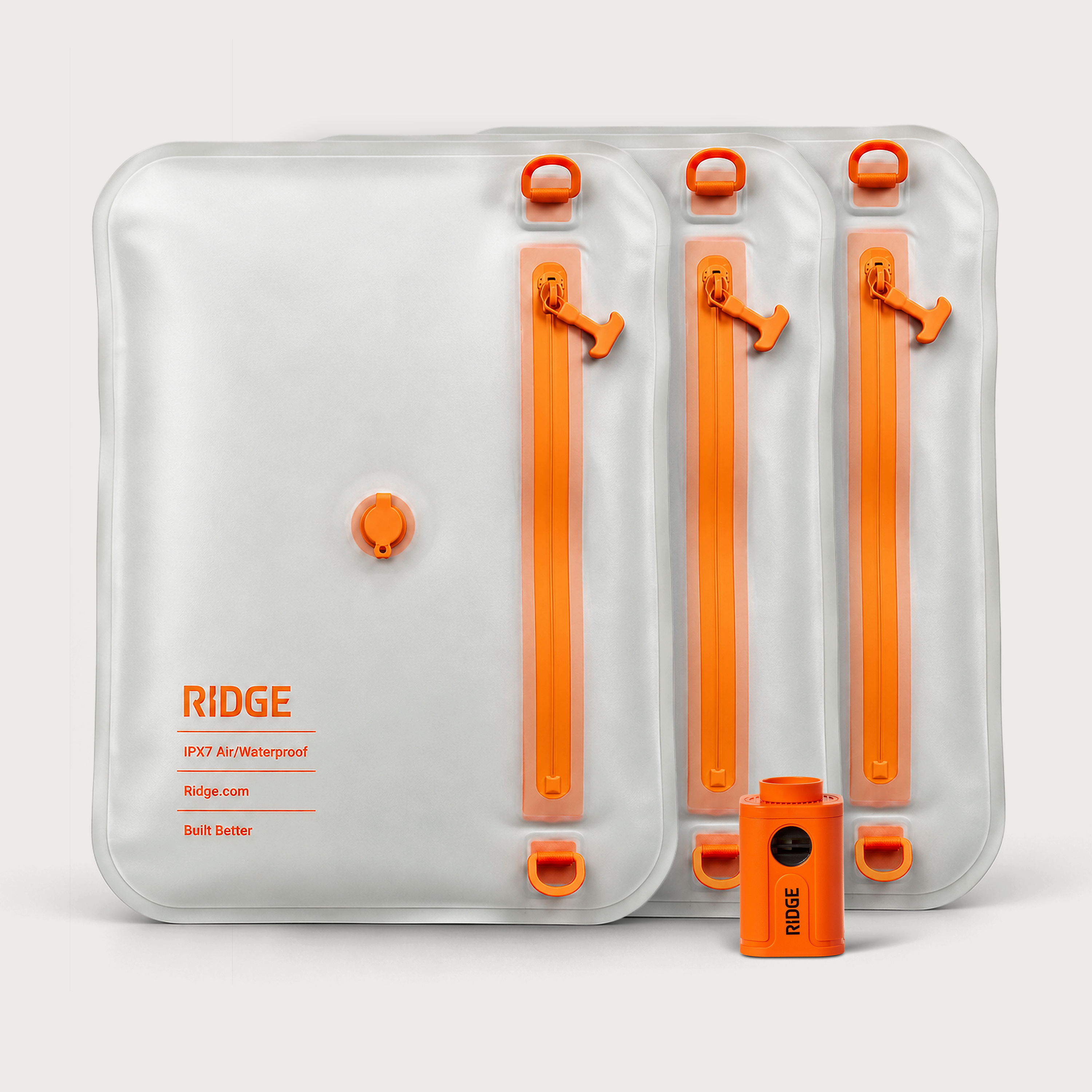 Three translucent Ridge waterproof pouches with orange zippers and a small orange air pump on a white background.