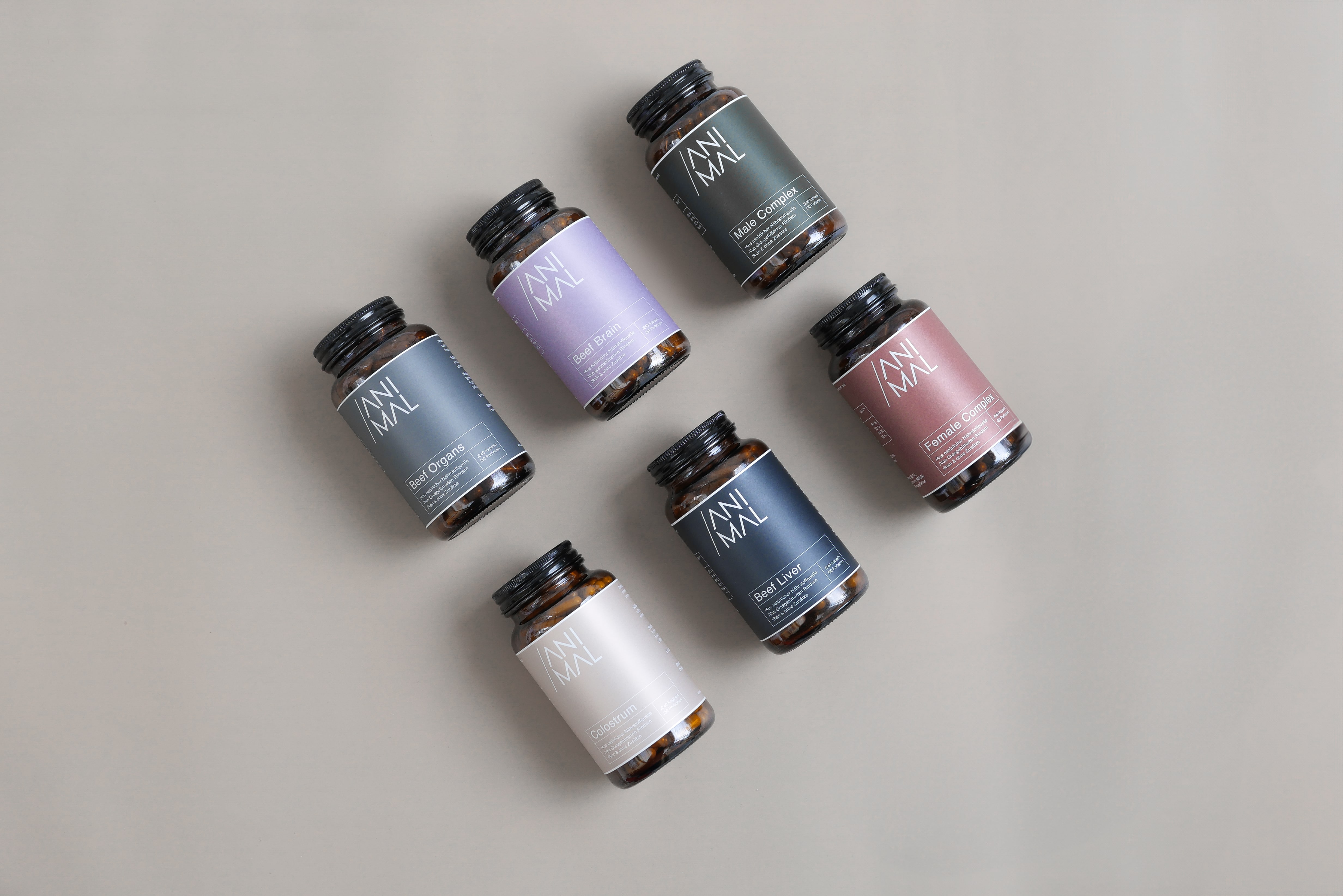 Six supplement bottles with different colored labels on a neutral background.
