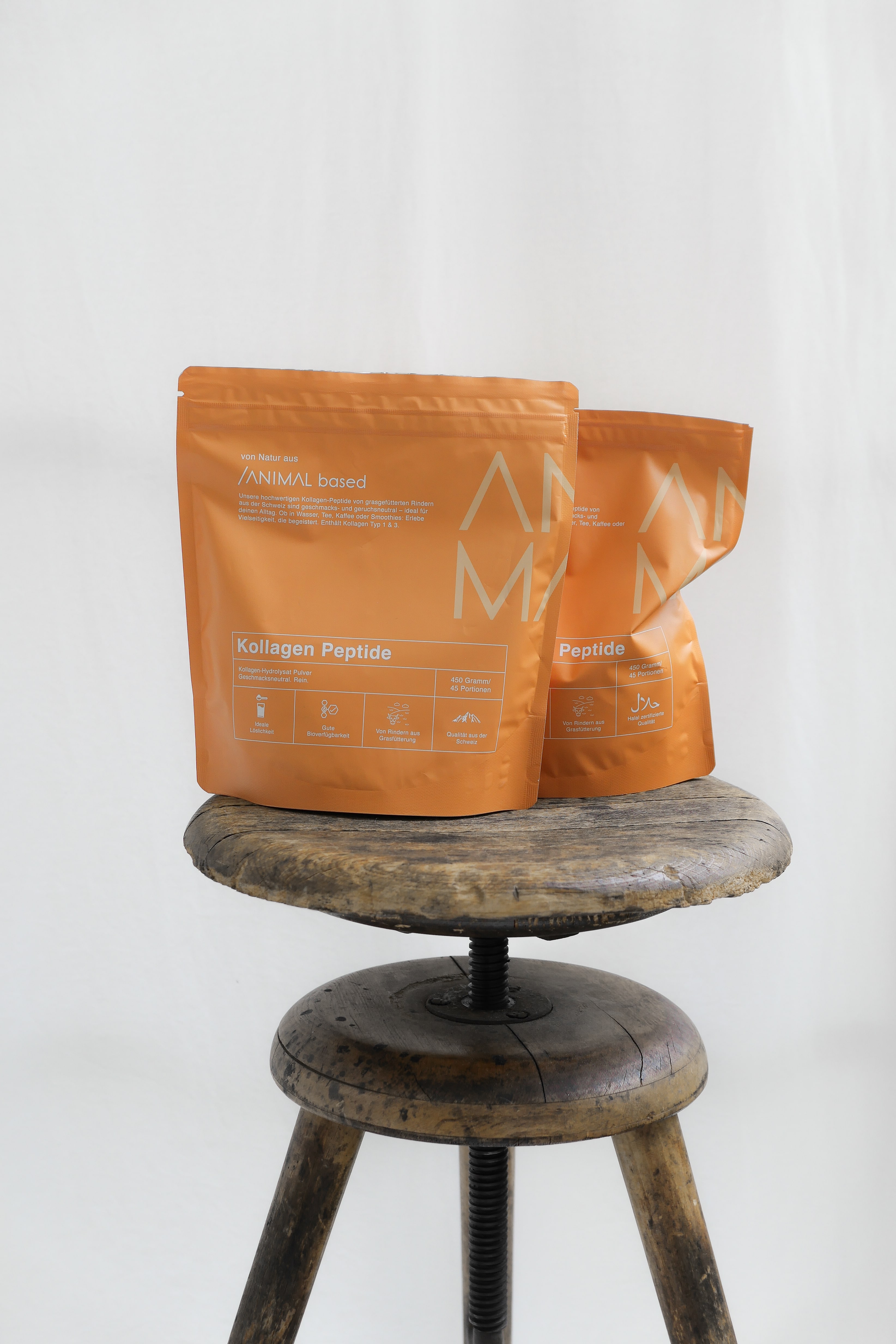 Two orange collagen peptide bags on a wooden stool.