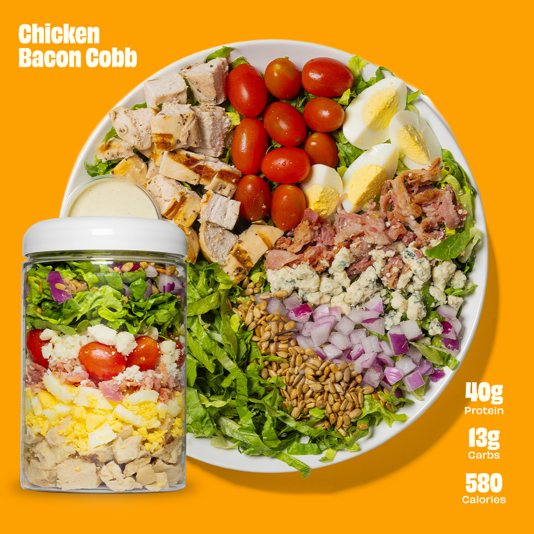 A single green leaf in a clear glass of water on a white background.