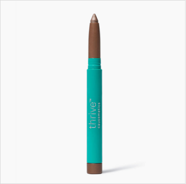 A Thrive Causemetics eyeshadow stick in a shimmery bronze shade with a teal tube against a white background.