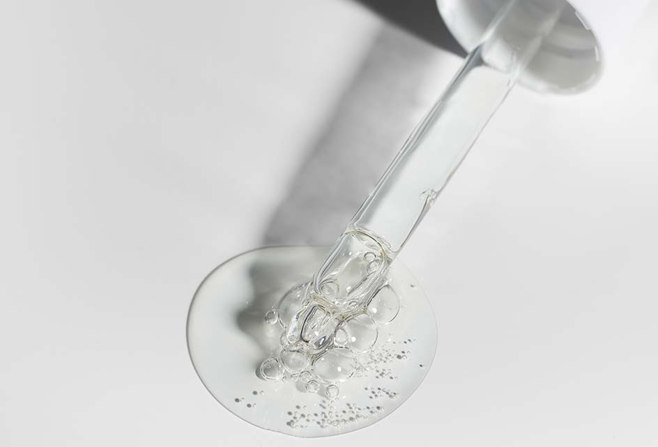 Clear liquid with bubbles and a dropper on a white surface.