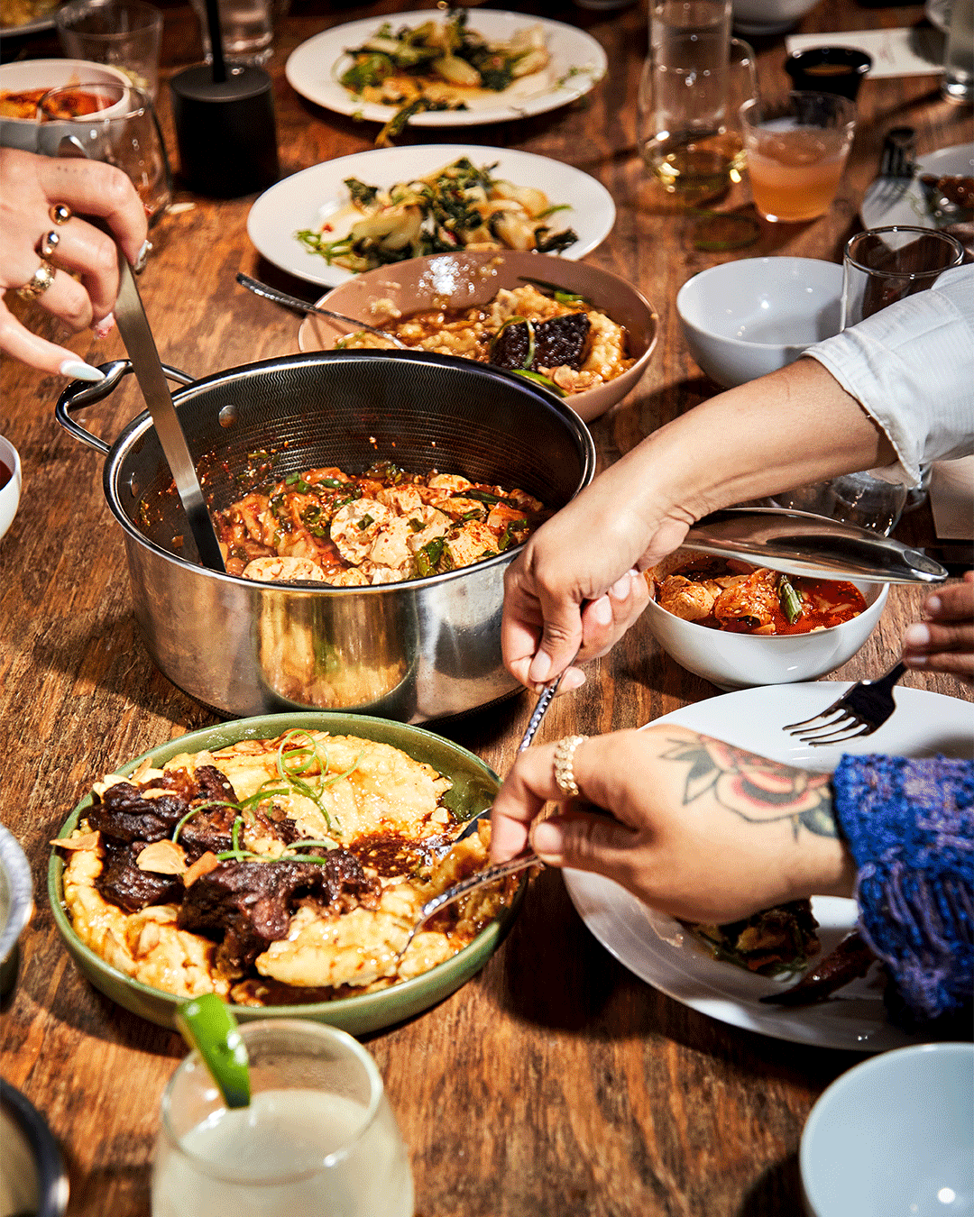 People sharing a meal with various dishes on a wooden table.