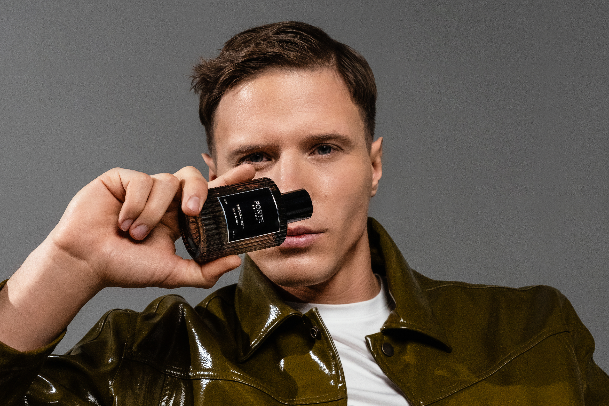 Person holding a perfume bottle close to their face.
