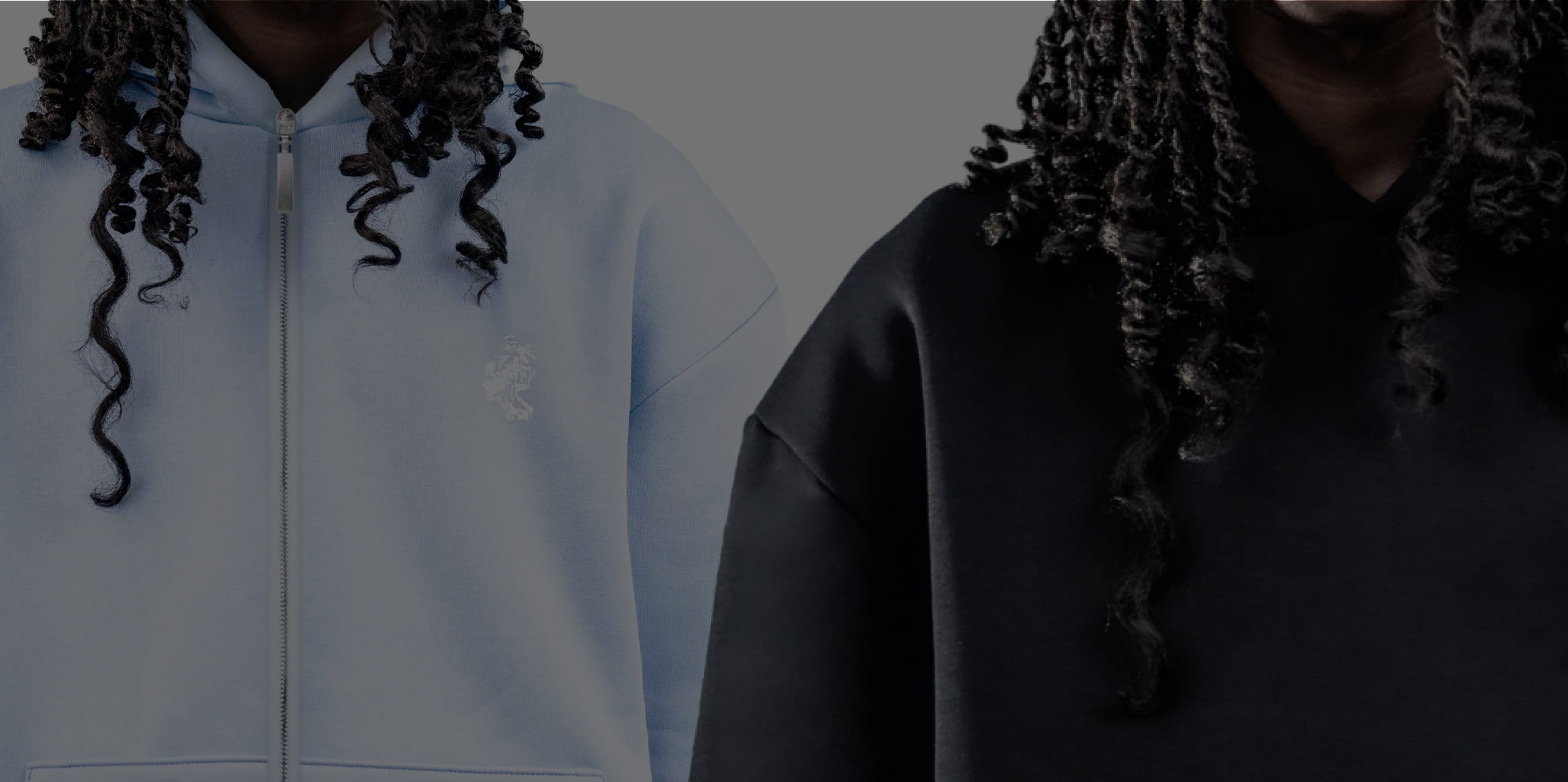 Two people wearing light blue and black hoodies with curly hair.