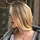 A person with long blonde hair looking to the side, wearing a gray hoodie.