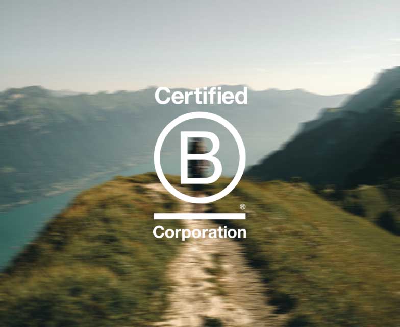 The Certified B Corporation logo overlaid on a blurry image of a person hiking in the mountains.
