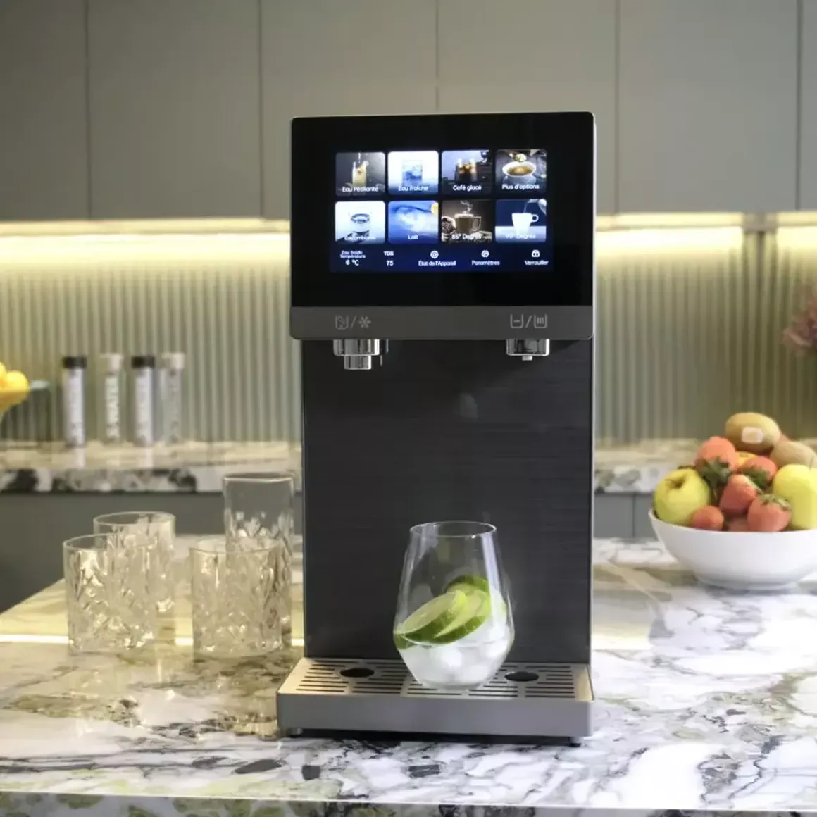A modern black water dispenser with a touchscreen sits on a kitchen counter with a glass of ice.