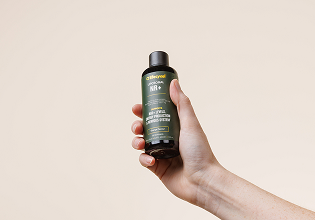 A hand reaches toward a black gift box containing five small dropper bottles with colorful labels.
