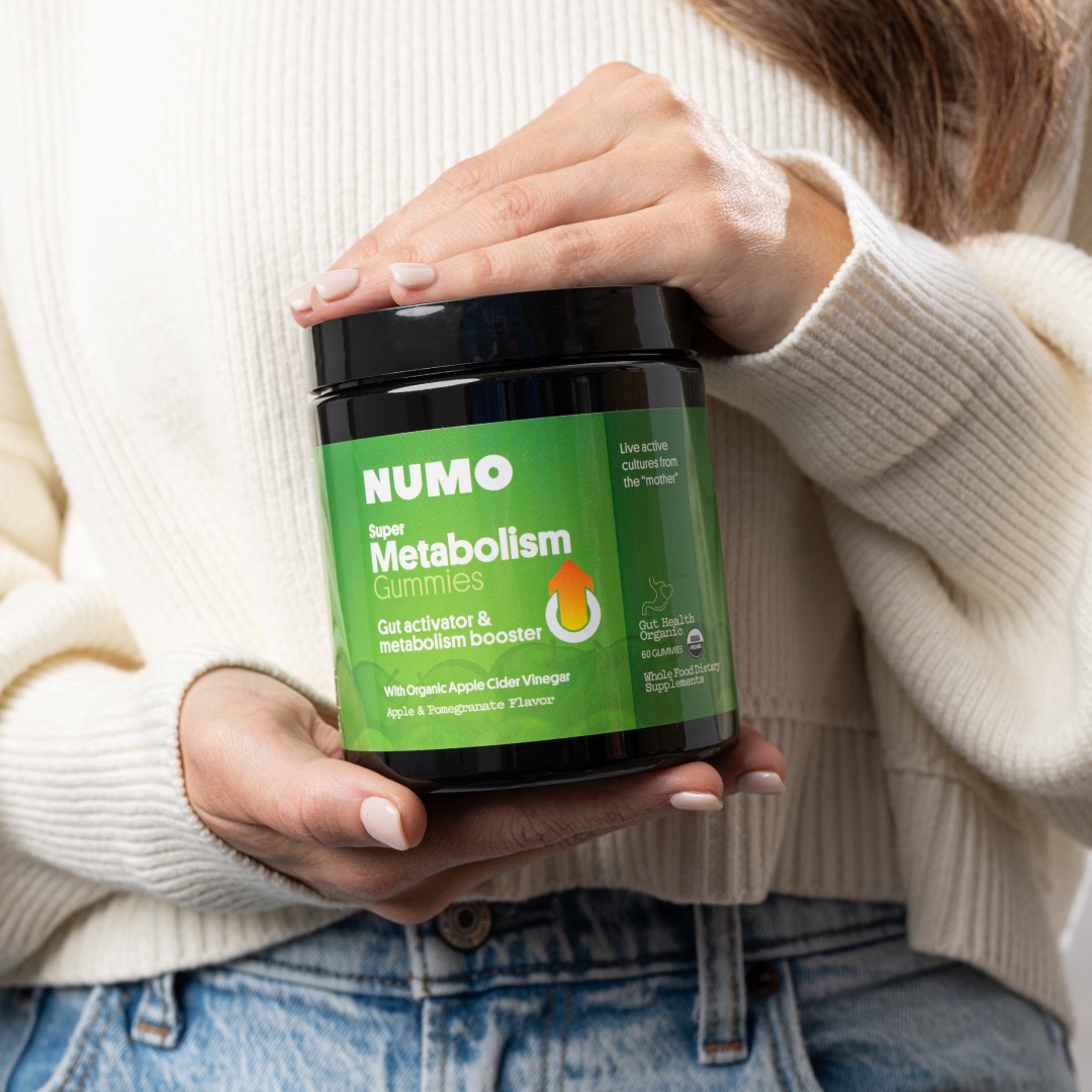Person holding a jar of NUMO Super Metabolism Gummies.