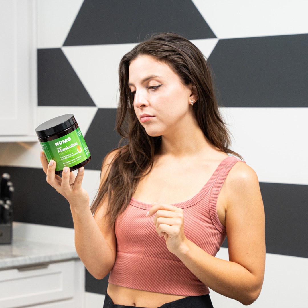 Person holding a green-labeled jar in a kitchen with geometric wall pattern.