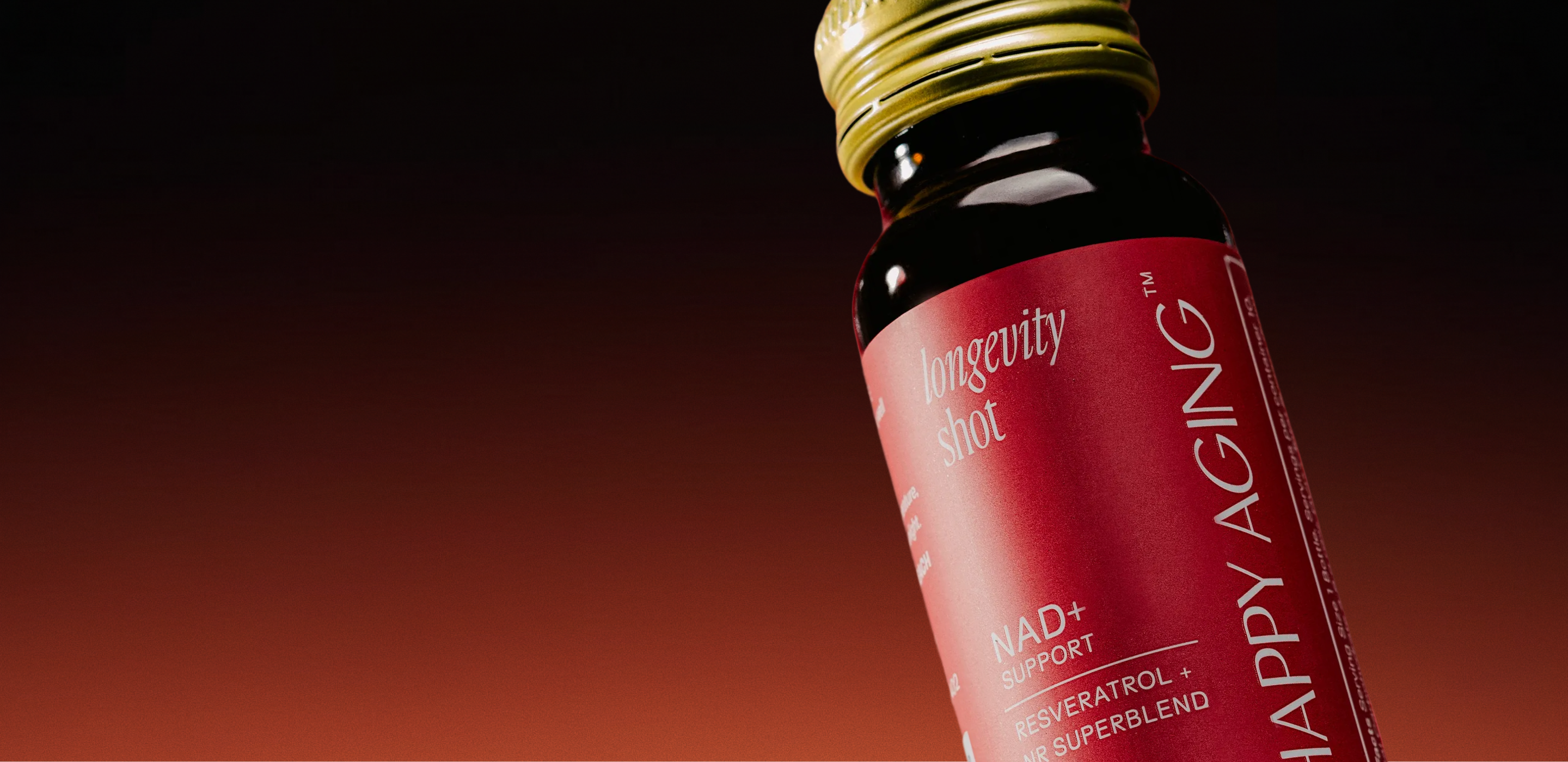 A close-up of a small bottle of 'longevity shot' with a red label and gold cap.