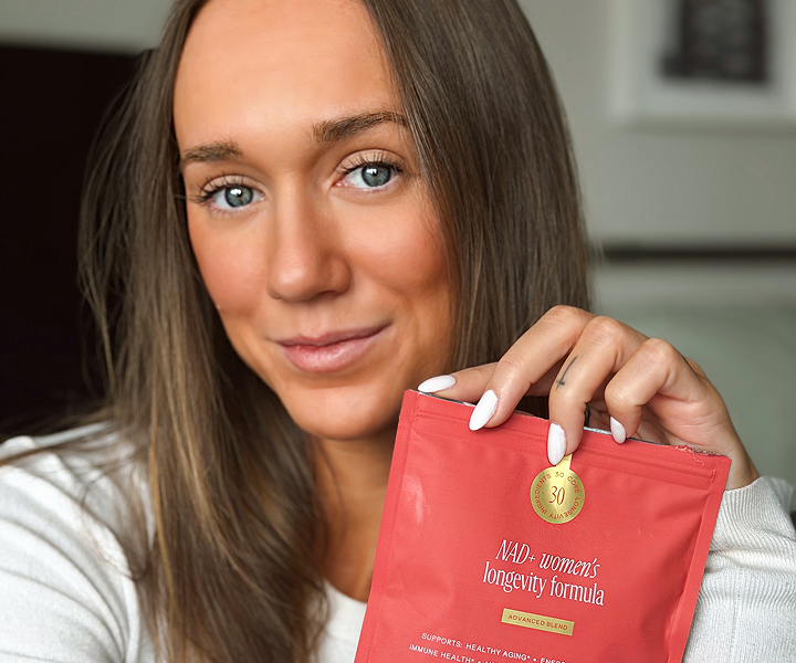 Person holding a red product package labeled 'NAD+ women's longevity formula.'