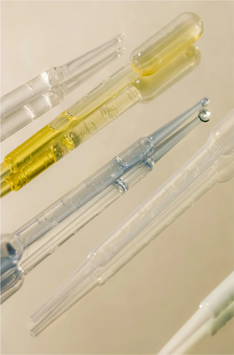 Close-up of pipettes with liquid inside, on a light background.