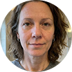 A circular headshot of a woman with wavy brown hair looking at the camera.