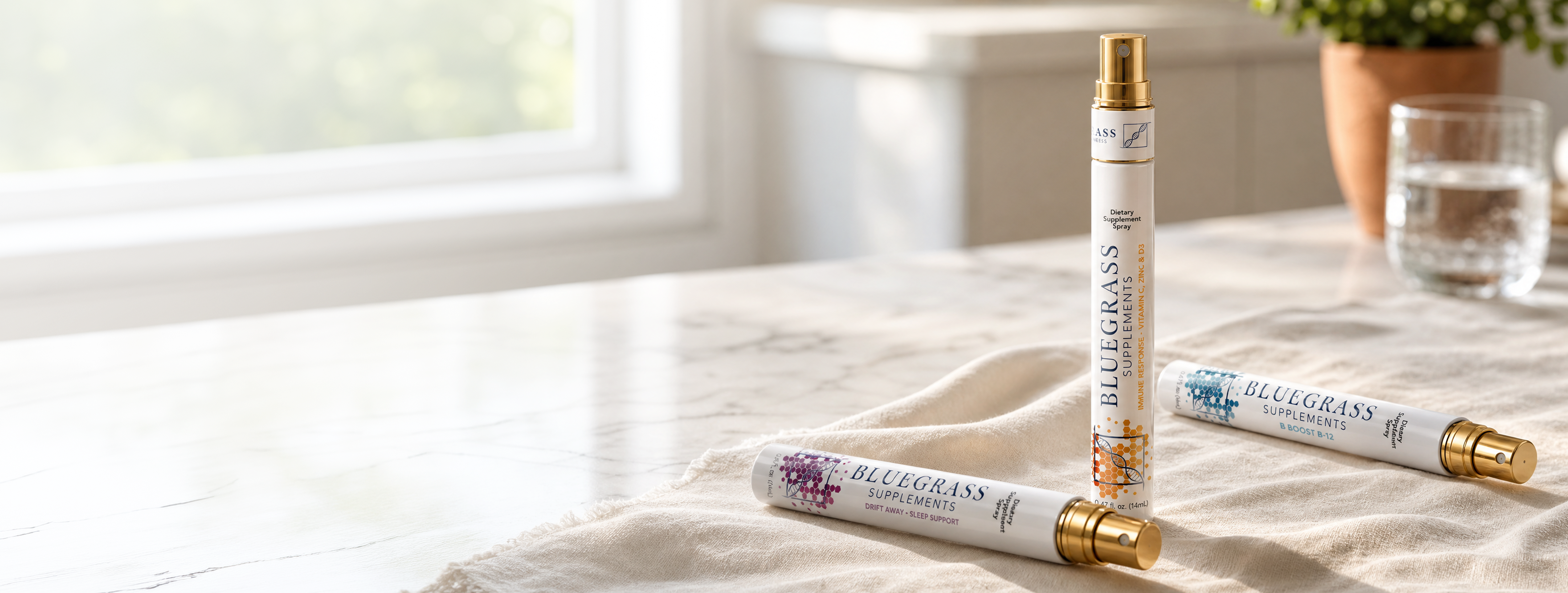 Three Bluegrass Supplements dietary supplement spray bottles are displayed on a marble countertop with a beige cloth.