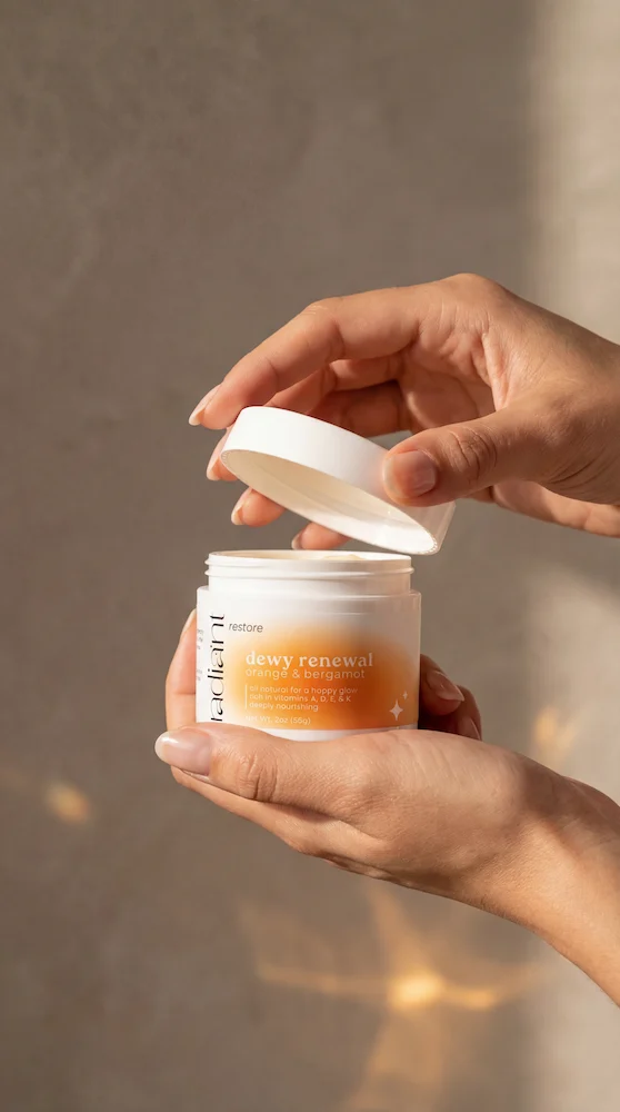 A person's hand holding a white and chrome handheld beauty device with a glowing red light.