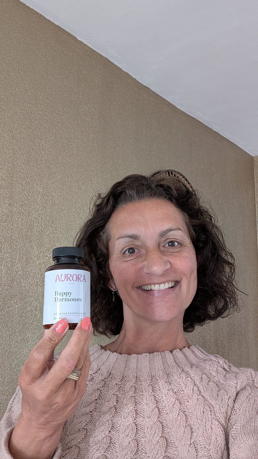 Person smiling and holding a bottle labeled 'Happy Hormones'.
