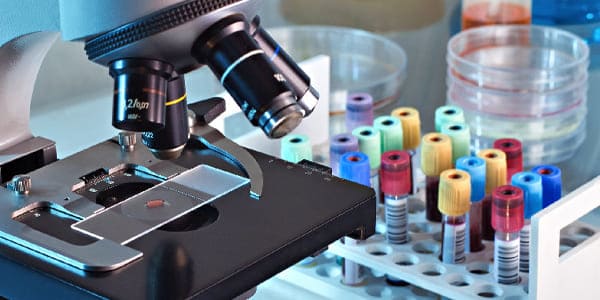 Microscope with test tubes and petri dishes in a laboratory setting.