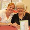 Two women smiling at a table with a greeting card.
