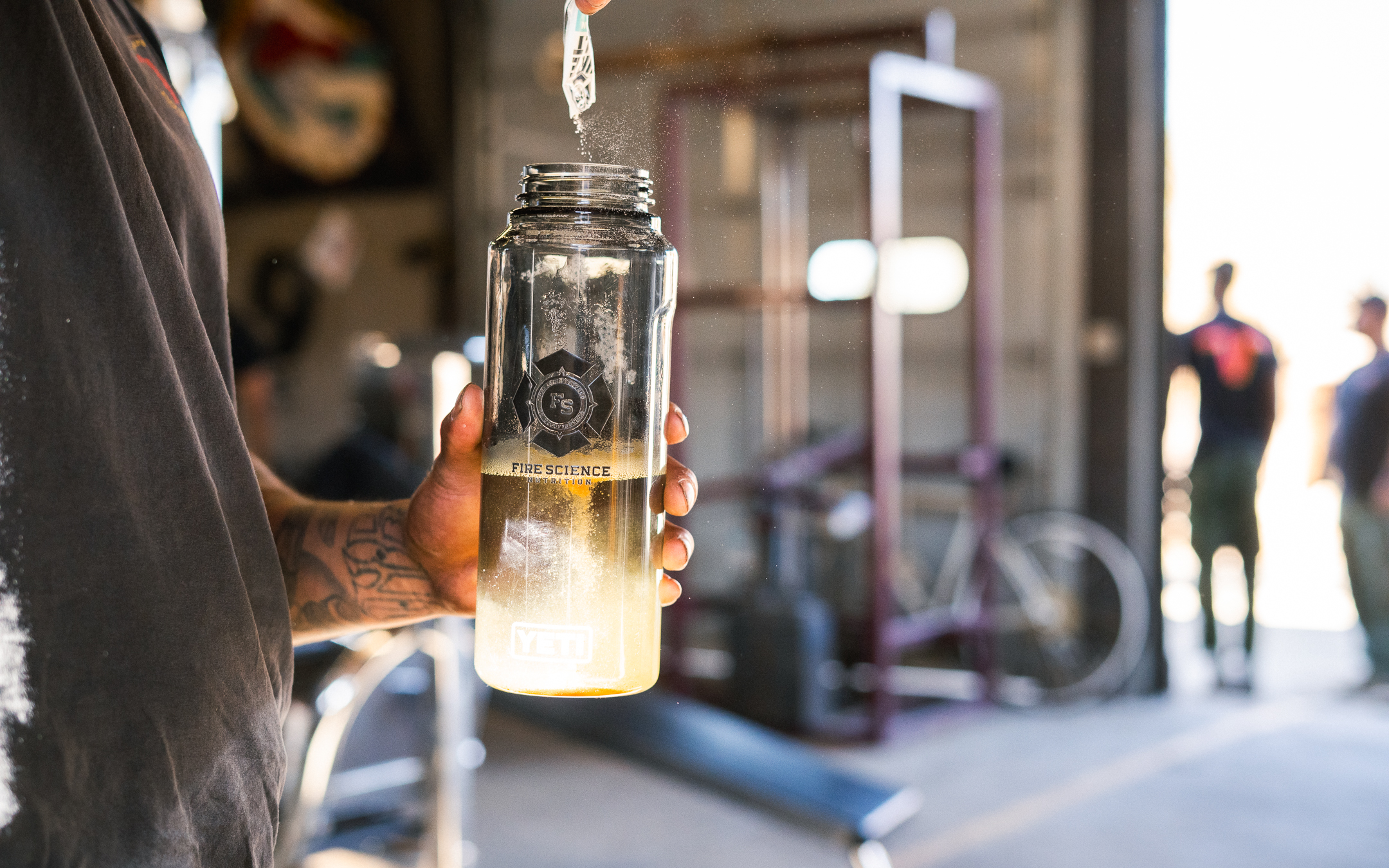 Person holding a clear bottle with liquid inside, in a workshop setting.