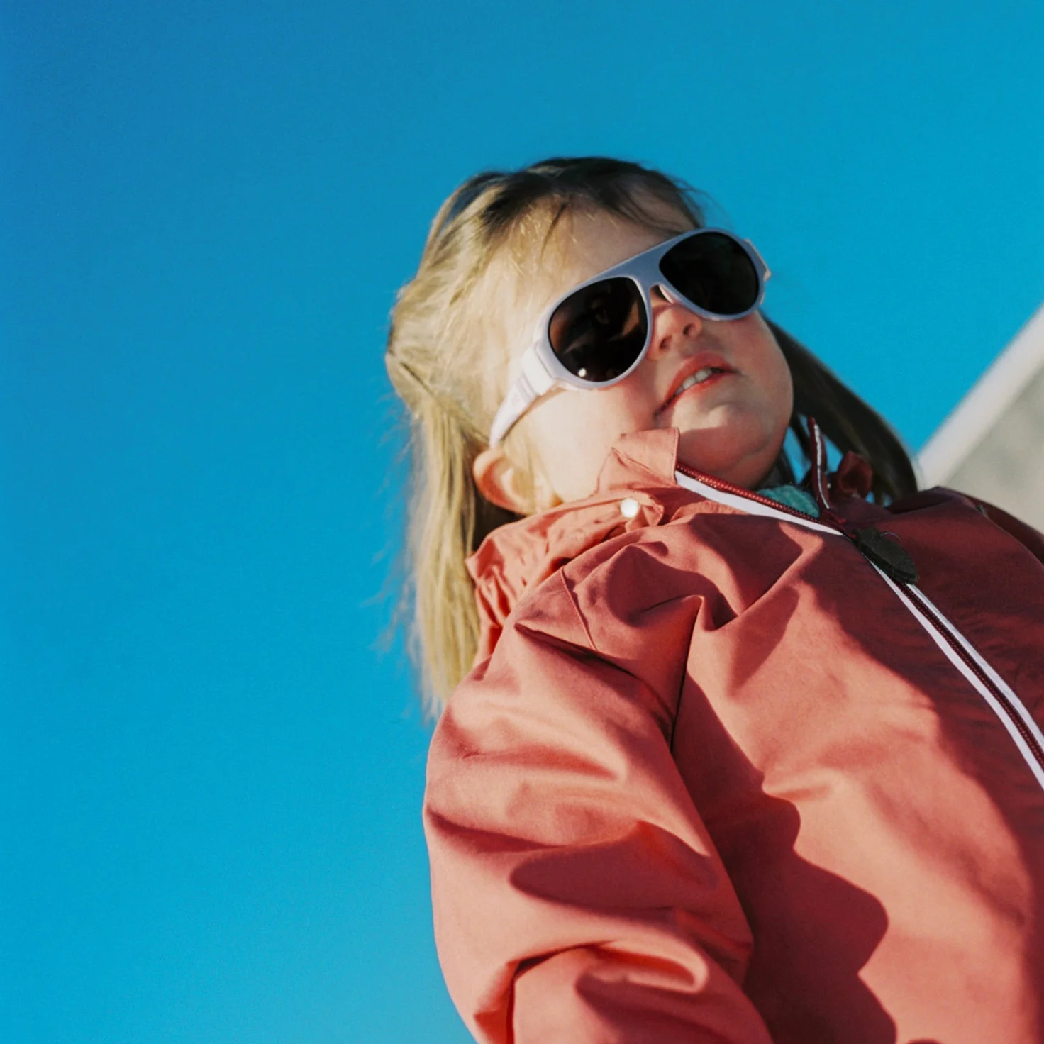 Girl wearing Click & Change sunglasses from Mokki against a clear blue sky.